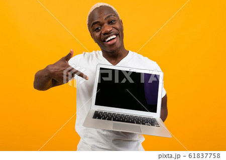 American in a white T-shirt shows a laptop display with a mockup on an orange background 61837758