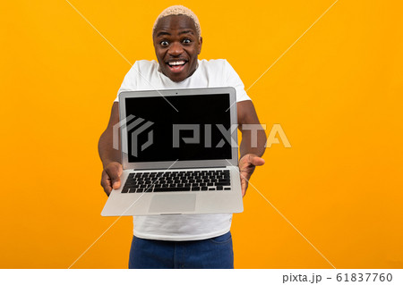 attractive joyful surprised american man in white t-shirt holds out his hands with laptop with 61837760