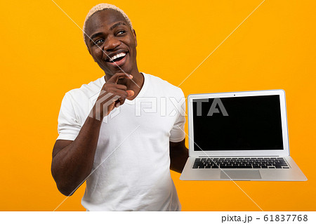 joyful smiling african man holding laptop with mockup on yellow background joyful smiling african man holding laptop with mockup on yellow background 61837768