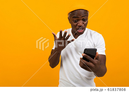 black man looks in surprise on the phone on an orange background black man looks in surprise on the phone on an orange background 61837808