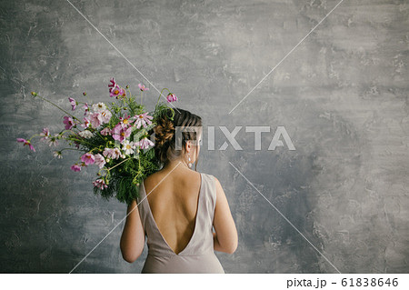 A young Beautiful Girl in a Pink Dress Holding a Delicate Bouquet of Flowers on a Gray Background 61838646