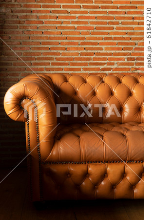 brown leather sofa with red brick wall indoor 61842710