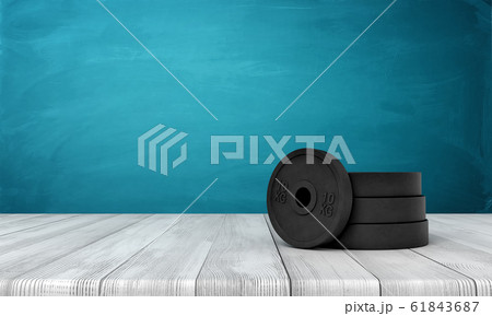 3d rendering of black weight plates on white wooden floor and dark turquoise background 61843687