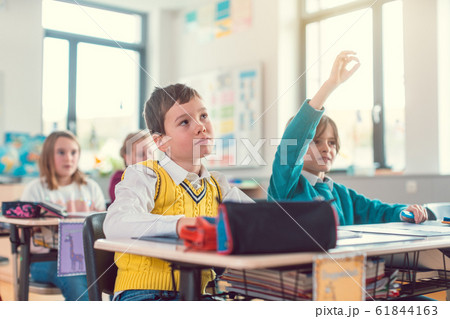 Boy student in class knowing an answer raising his hand 61844163