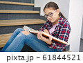 Girl is reading book while sitting on stairs 61844521