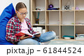 Girl is reading book while sitting in room 61844524