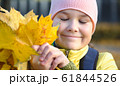 Cute little girl in autumn park holding bunch of 61844526