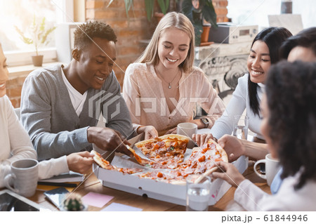Happy multiracial colleagues eating pizza in office 61844946