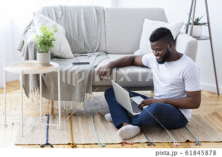 Positive african man surfing internet on laptop 61845878