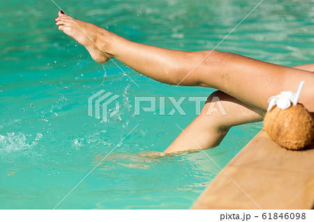 Legs of sexy girl with coconut sit at simmingpool 61846098