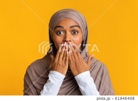 Shocked afro muslim woman in hijab covering her mouth with hands 61846408