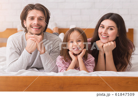 Happy family of three posing on bed at home together 61847509