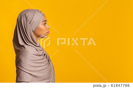 Profile portrait of black muslim woman in hijab over yellow background 61847766