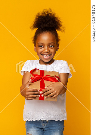 Cheerful afro girl holding gift box, yellow background Cheerful afro girl holding gift box, yellow background 61848175