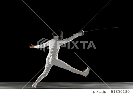 Teen girl in fencing costume with sword in hand isolated on black background Teen girl in fencing costume with sword in hand isolated on black background 61850180