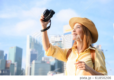 Young woman taking photograph against buildings in background in Singapore Young woman taking photograph against buildings in background in Singapore 61850206