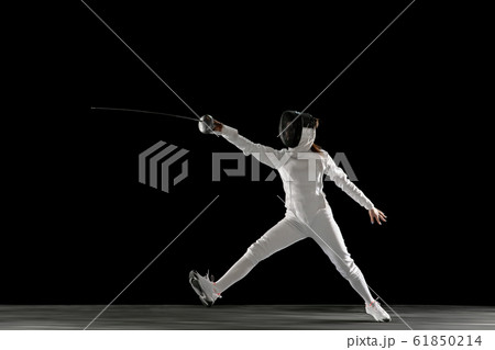 Teen girl in fencing costume with sword in hand isolated on black background Teen girl in fencing costume with sword in hand isolated on black background 61850214