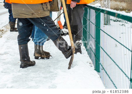 man shovel cleans the sidewalk from snow. 61852386