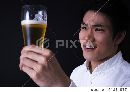 ビールを飲む若いビジネスマン（黒バック、ネクタイ、グラスビール 61854857