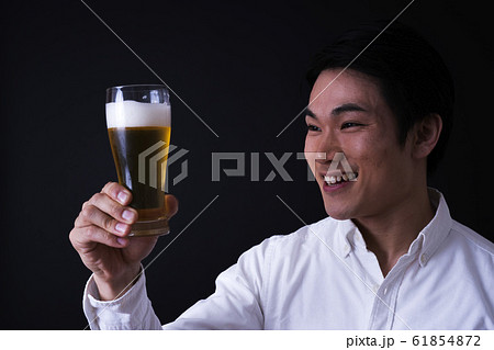 ビールを飲む若いビジネスマン（黒バック、ネクタイ、グラスビール 61854872