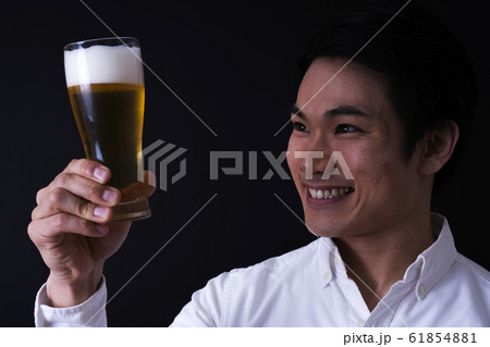 ビールを飲む若いビジネスマン（黒バック、ネクタイ、グラスビール 61854881
