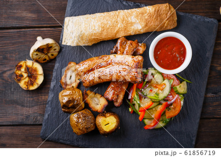 Grilled ribs with potatoes and vegetable salad Grilled ribs with potatoes and vegetable salad 61856719