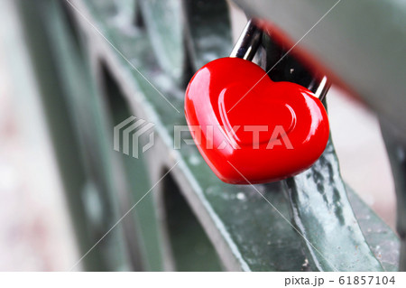 Red Valentine's Day Heart shape wedding lock hangs on metal bridge of lovers on blurred background. 61857104