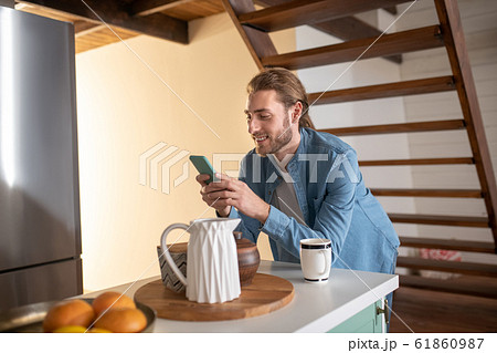 Smiling man updating his status while having a morning tea 61860987