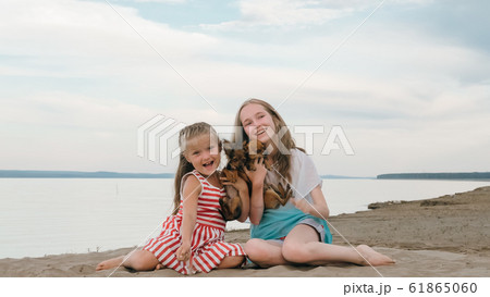 Two children playing which dogs on the sand on the beach. 61865060