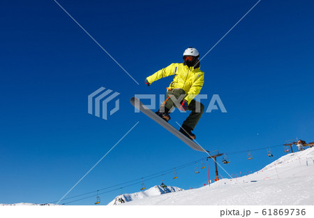 Bright color snowboarder jumps on blue sky Bright color snowboarder jumps on blue sky 61869736
