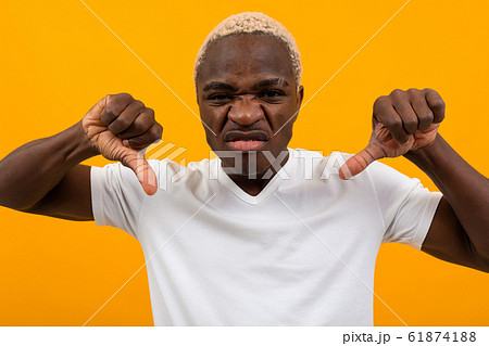 portrait of a blond displeased charismatic african man in a white t-shirt holding his fingers down portrait of a blond displeased charismatic african man in a white t-shirt holding his fingers down 61874188