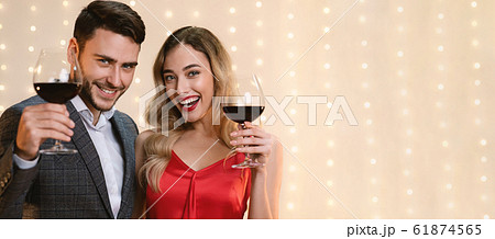 Young Couple Posing With Red Wine Glasses Over Beige Background 61874565