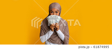 Happy Black Muslim Woman In Headscarf Covering Face With Dollar Cash 61874995