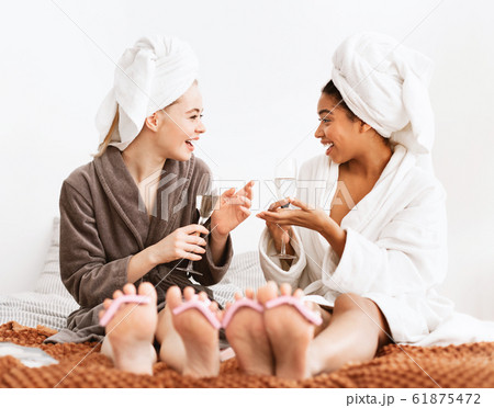 Two young women having spa day together, drinking champagne Two young women having spa day together, drinking champagne 61875472
