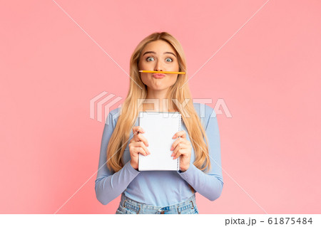 Cheering teen holding pen as moustache over pink wall Cheering teen holding pen as moustache over pink wall 61875484