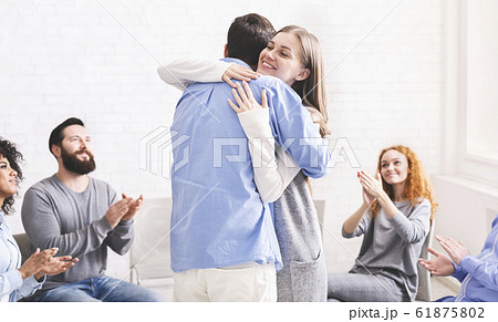 Happy spouses cuddling each other after group meeting with relationship therapist. Happy spouses cuddling each other after group meeting with relationship therapist. 61875802