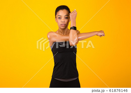 Woman Exercising Stretching Deltoid Arm Muscle Posing Over Yellow Background 61876146