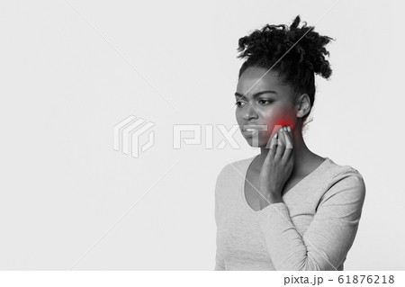 Young black woman touching cheek, feeling pain Young black woman touching cheek, feeling pain 61876218