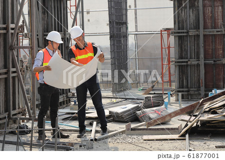 Two engineers work on the construction site. They Two engineers work on the construction site. They 61877001