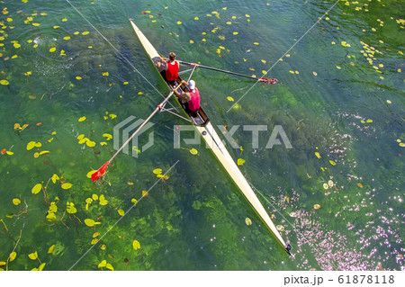 Two young athletes rowing team on green lake 61878118
