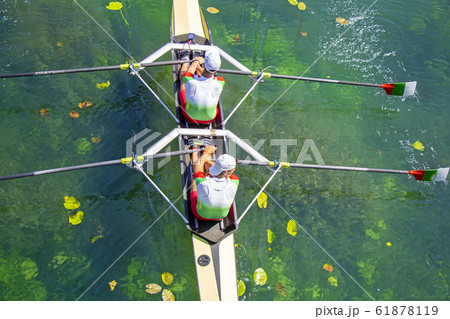 Two young athletes rowing team on green lake Two young athletes rowing team on green lake 61878119