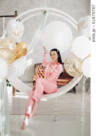 Gorgeous girl in pink pyjamas on hanging chair. Gorgeous girl in pink pyjamas on hanging chair. 61879787
