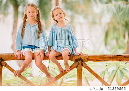 Little happy funny girls have a lot of fun at tropical beach playing together. Sunny day with rain in the sea Little happy funny girls have a lot of fun at tropical beach playing together. Sunny day with rain in the sea 61879866