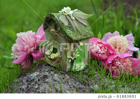 Decorated fairy house and beautiful peony flowers. Lovely miniature house for greeting cards, wedding or birthday concept. Vintage summer background Decorated fairy house and beautiful peony flowers. Lovely miniature house for greeting cards, wedding or birthday concept. Vintage summer background 61883691
