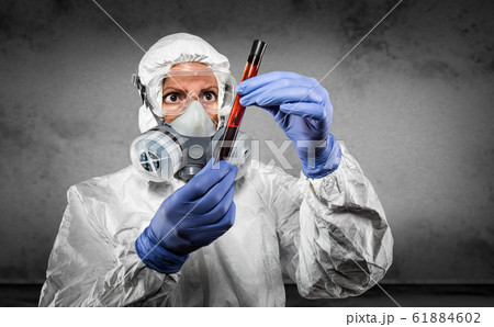 Woman In Hazmat Suit and Gas Mask Holding Test Tube Woman In Hazmat Suit and Gas Mask Holding Test Tube 61884602