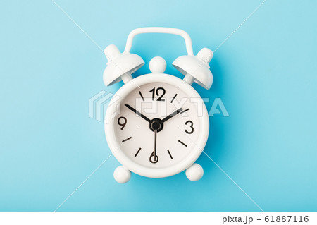 White retro alarm clock on blue background. White retro alarm clock on blue background. 61887116