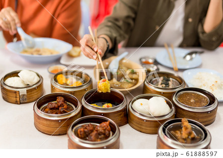 Hand holding chopsticks with steamed dumplings dim sum food in restaurant. Hand holding chopsticks with steamed dumplings dim sum food in restaurant. 61888597