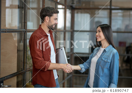 Young girl in jeans jacket giving hand to her colleague 61890747