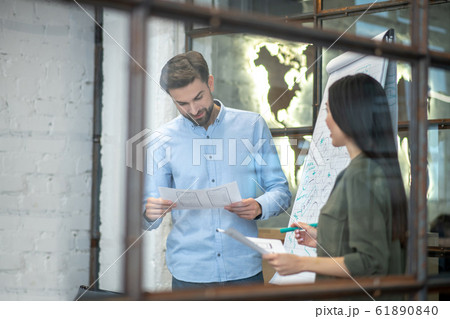 Bearded man in a blue shirt reading something in the office Bearded man in a blue shirt reading something in the office 61890840