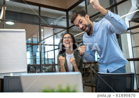 Tall young man and his female colleague feeling happy in the office 61890870